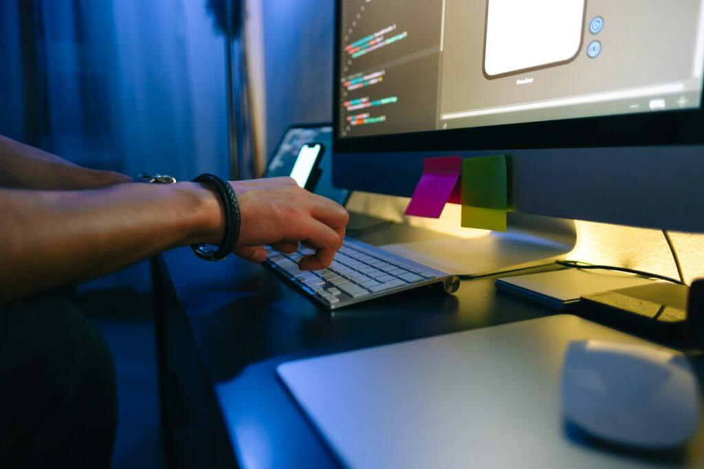 Mobile developer writes program code on a computer, typing on keyboard