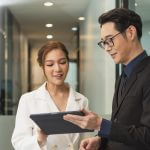 Smiling asian businesswoman showing tablet to her manager during