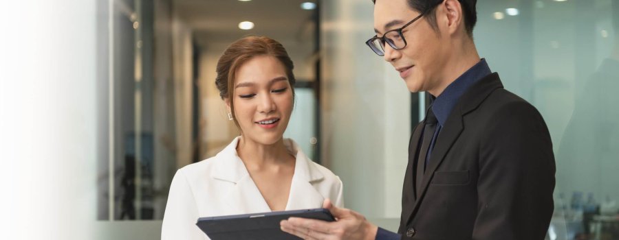 Smiling asian businesswoman showing tablet to her manager during